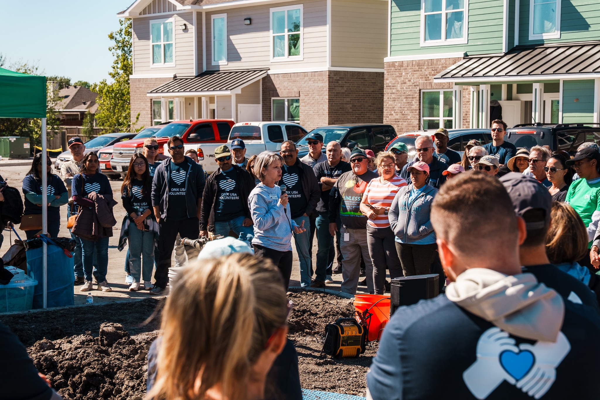 Large group of volunteers surrounding speaker during a volunteer effort.